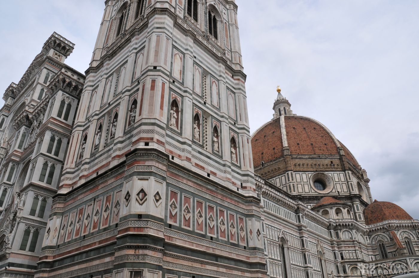 Das Bild zeigt den Florentiner Dom mit roter Kuppel und kunstvoller Marmor-Fassade unter bewölktem Himmel.