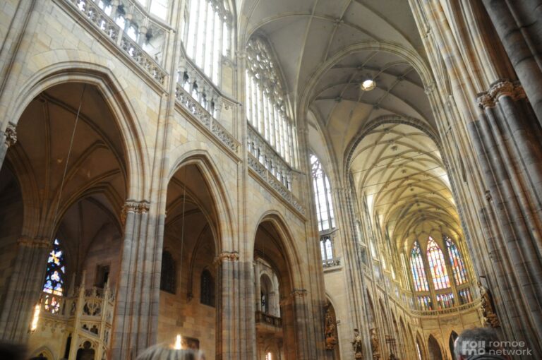 Große gotische Kathedrale mit hohen Gewölbedecken, bunten Fenstern und Steinbögen; imposante Kircheninnere.