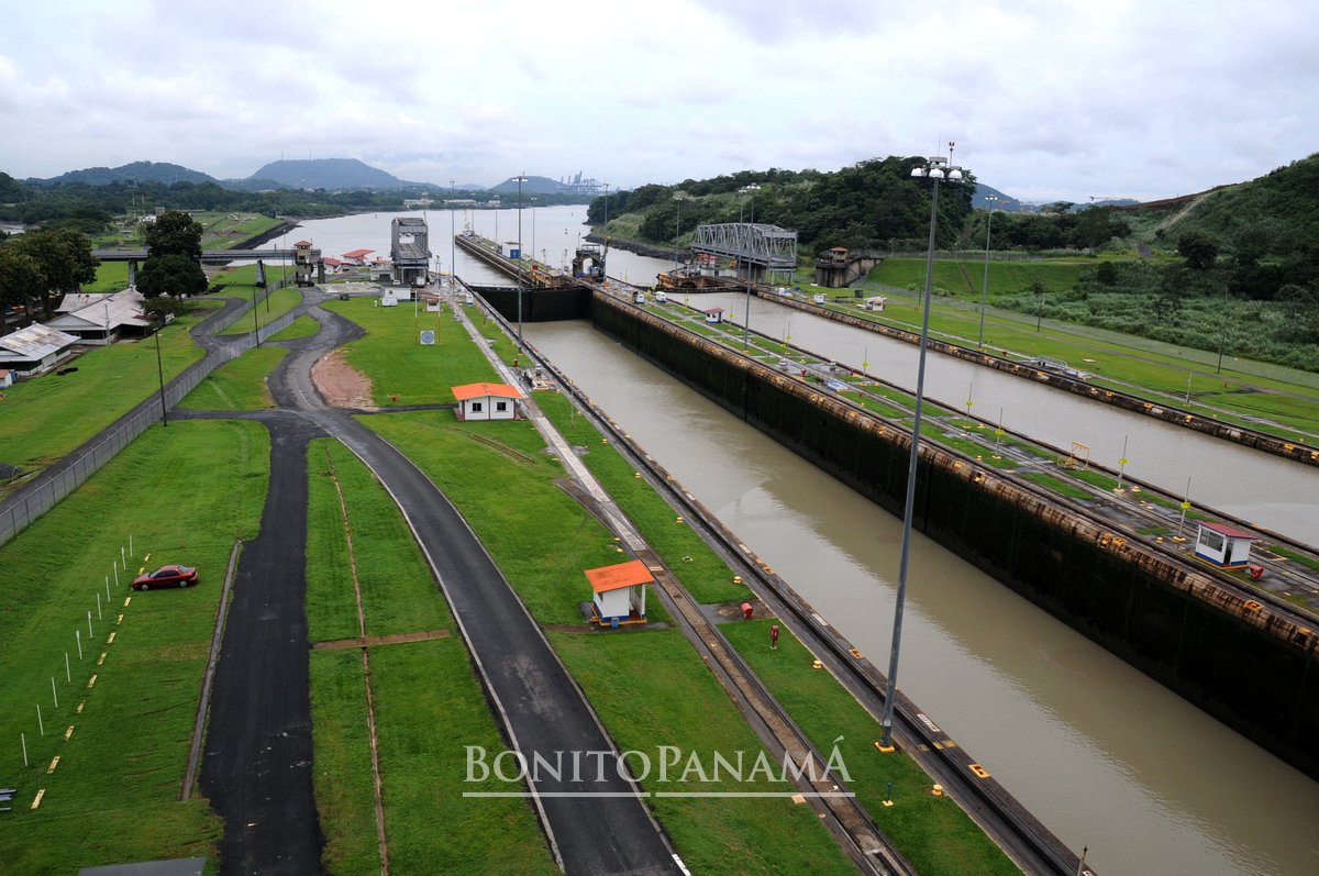 Panama-Kanal mit offenen Schleusen, umgeben von Grün, Straßen und Gebäuden; unten steht "Bonito Panama".
